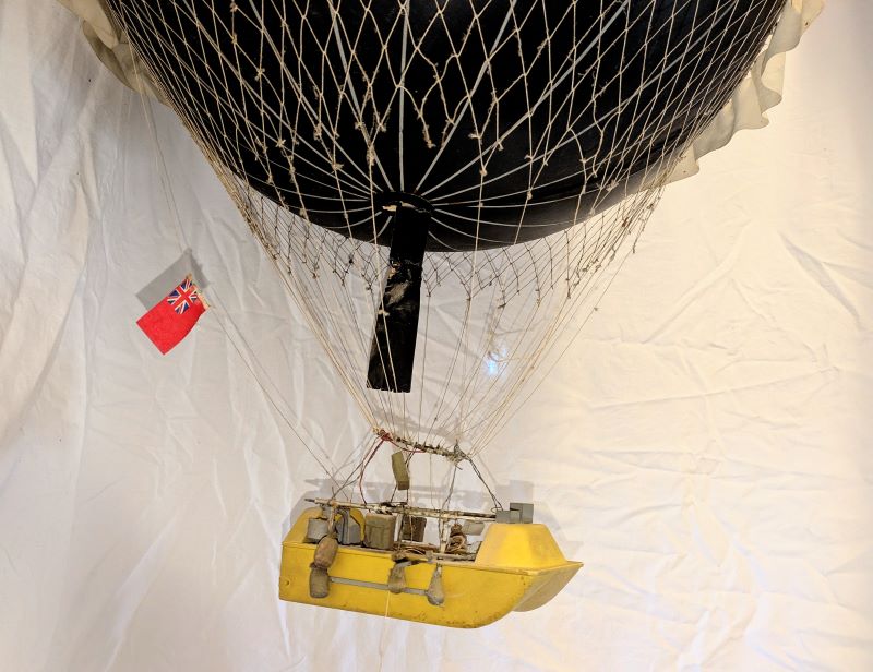 A close up picture of the yellow boat-shaped gondola suspended beneath the balloon containing sand bags and instruments